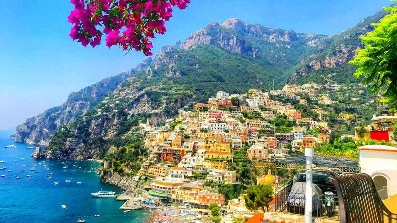 Positano seen from the coast road with bougainvillea in front, the morning drive on Pompeii tours from Rome that visit the coast before the ruins, Italy