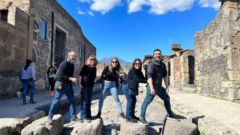 Small group posing among the ruined houses of Pompeii before the winery lunch on Pompeii tours from Rome with wine tasting by train, Italy